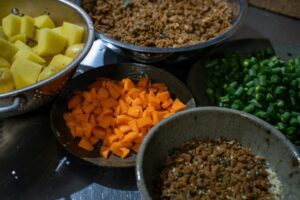 Chopped vegetables and ground meat in bowls.