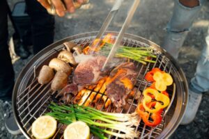 Grilling steak and vegetables on outdoor barbecue.