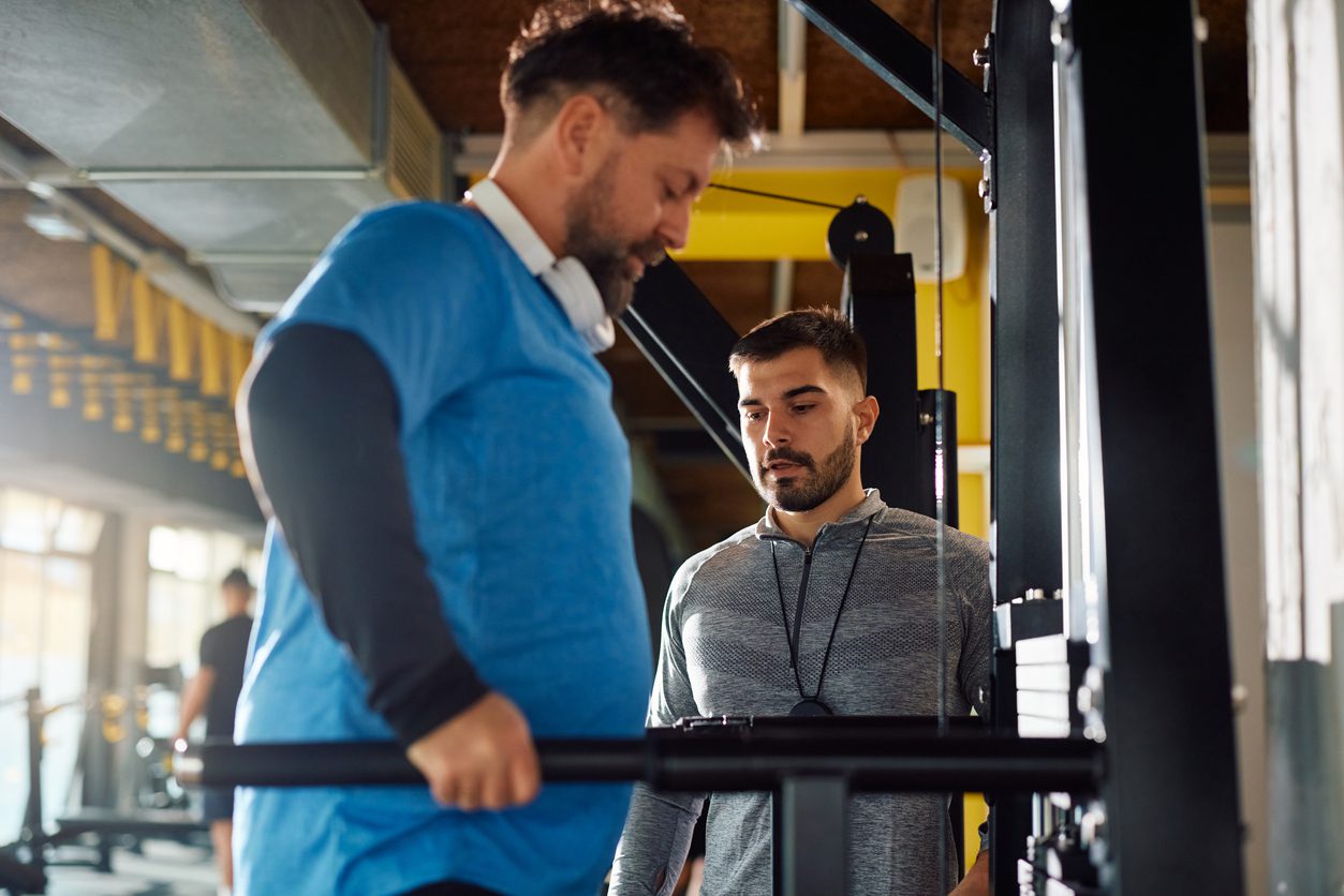 Persona trainer during mature man's sports training in a gym.