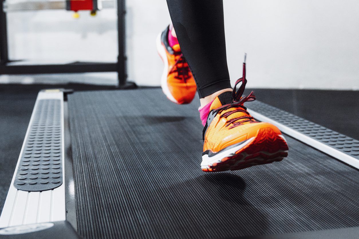 Close up of a person jogging on a treadmill in fitness center. Warming up with some cardio training.