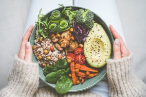A colorful bowl with avocado, vegetables, and grains.