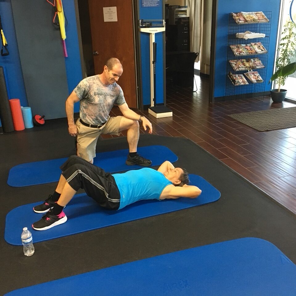 Two men exercising on mats in a gym.