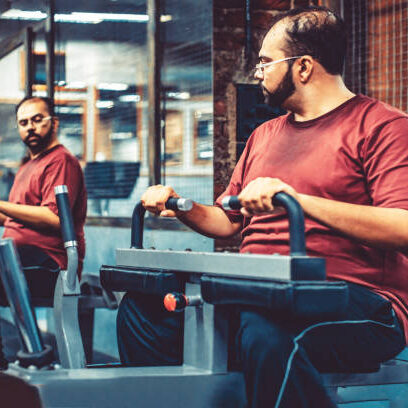 India, Fitness, Healthy Lifestyle - Overweight Man at a fitness centre looking at the mirror and imaging himself getting slim